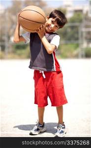 Boy with basketball on his shoulders, outdoors