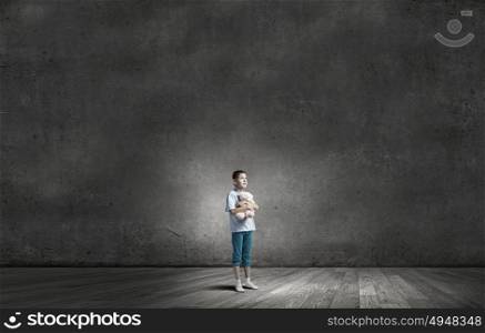 Boy with bear toy. Cute little boy with toy bear in concrete dark room