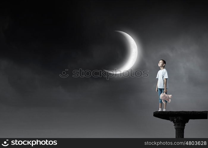 Boy with bear toy. Cute little boy with toy bear in night darkness