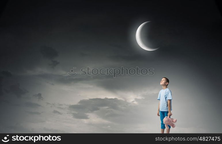 Boy with bear toy. Cute little boy with toy bear in night darkness