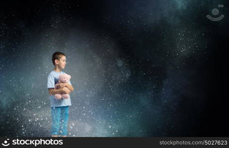 Boy with bear toy. Cute little boy with toy bear in night darkness