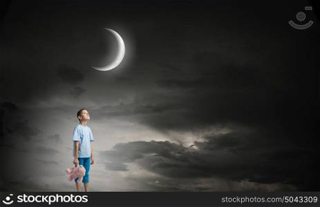 Boy with bear toy. Cute little boy with toy bear in night darkness