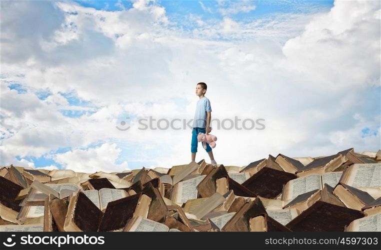 Boy with bear toy. Cute little boy with toy bear on pile of books