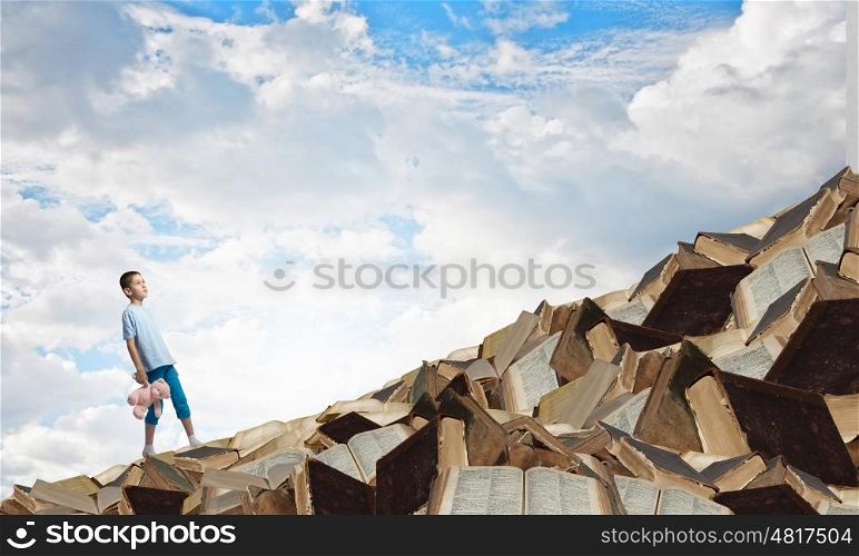 Boy with bear toy. Cute little boy with toy bear on pile of books