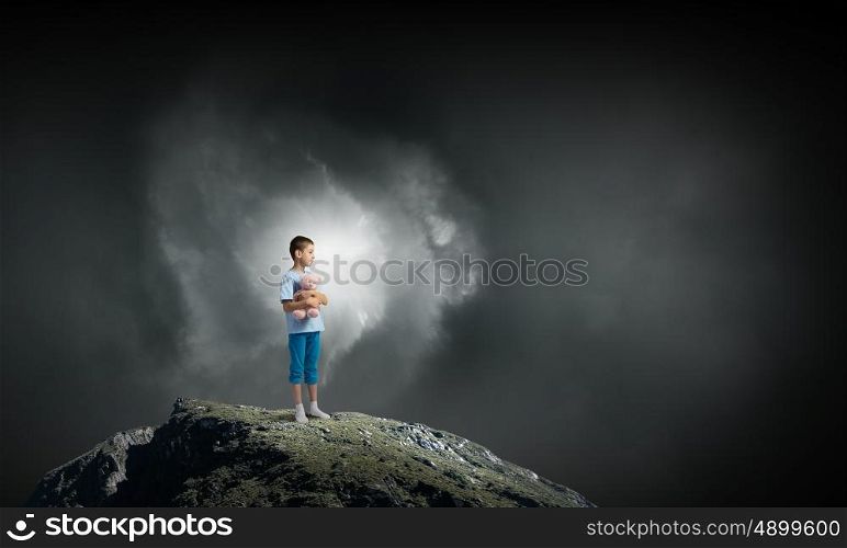 Boy with bear toy. Cute little boy with toy bear on rock top