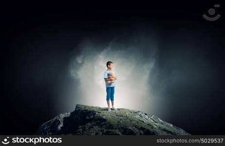 Boy with bear toy. Cute little boy with toy bear on rock top