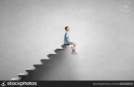 Boy with bear toy. Cute little boy with toy bear sitting on ladder of books