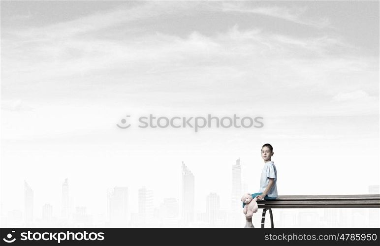 Boy with bear toy. Cute little boy with toy bear sitting on wooden bench