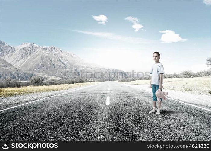 Boy with bear toy. Cute little boy with toy bear standing on asphalt road