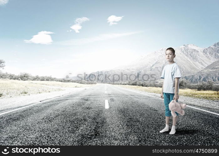 Boy with bear toy. Cute little boy with toy bear standing on asphalt road