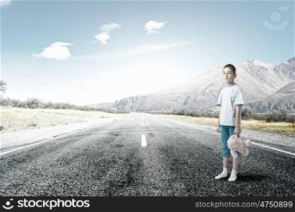 Boy with bear toy. Cute little boy with toy bear standing on asphalt road