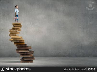 Boy with bear toy. Cute little boy with toy bear standing on pile of books