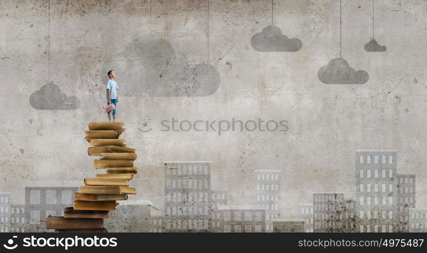 Boy with bear toy. Cute little boy with toy bear standing on pile of books