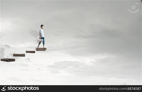 Boy with bear toy. Cute little boy with toy bear walking on ladder of books