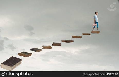 Boy with bear toy. Cute little boy with toy bear walking on ladder of books