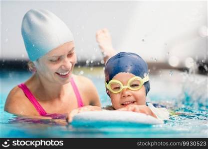 Boy with borad splashing on swimming class with instructor