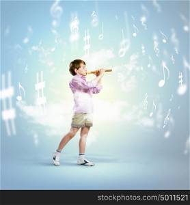 Boy with flute. Image of little cute boy playing on flute against cloudy background