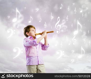 Boy with flute. Image of little cute boy playing on flute against cloudy background