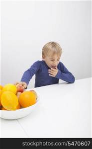 Boy with fruit bowl sneezing at table