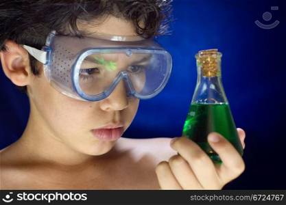 Boy with glass looks scientific experiment in test tubes on blue background