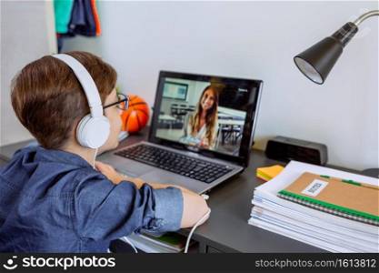 Boy with headphones receiving class at home with laptop from his bedroom. Home schooling concept