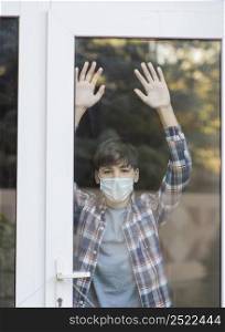 boy with medical mask looking outside