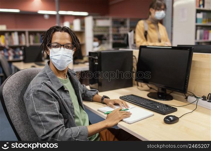 boy with medical mask studying library