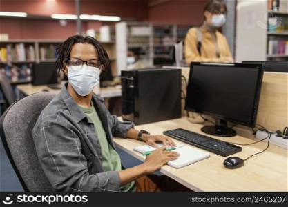 boy with medical mask studying library