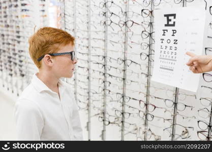 boy with spectacle looking snellen chart while doctor s hand pointing chart