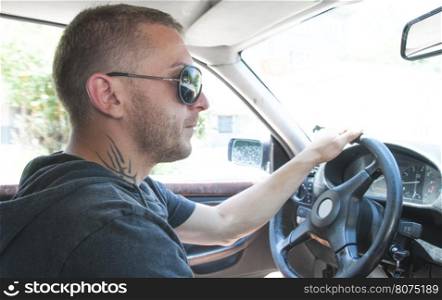 Boy with sunglasses driving a car. Close up