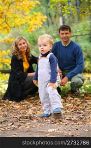 boy with untied lace and parents in autumn park