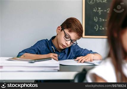 Boy writing in his notebook at school. Selective focus on boy in background. Boy writing in notebook at school