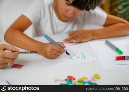 Boy writing letters on preschool screening test.. Screening test for preschool children.