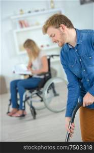 boyfriend helping wheelchair girlfriend to do hoovering