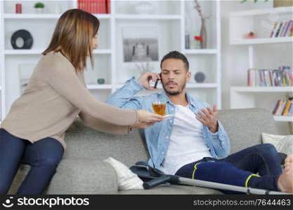 boyfriend on the phone while girlfriend offers tea