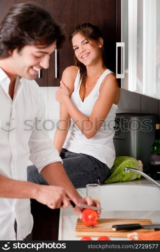 boyfriend sliceing tomottos with his girlfriend in kitchen..