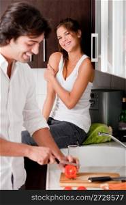 boyfriend sliceing tomottos with his girlfriend in kitchen..