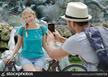boyfriend taking a picture of his girlfriend background the fountain