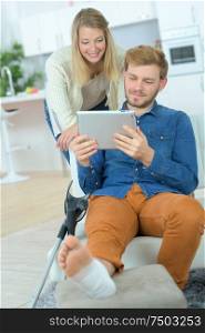 boyfriend with broken leg playing with girlfriend on tablet