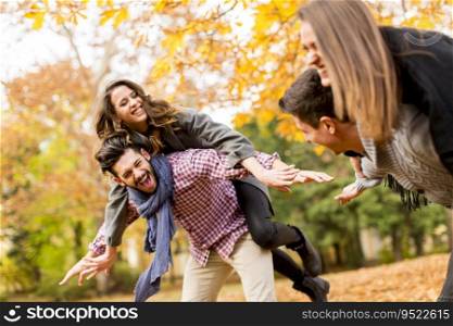 Boyfriends holding girlfriends on back in autumn park and having fun