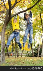 boys hanging from branch of tree