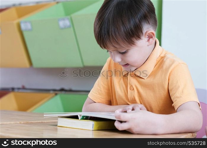 Boys reading book in their kindergarten classroom, kid education concept
