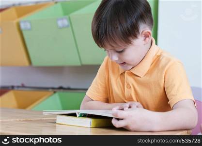 Boys reading book in their kindergarten classroom, kid education concept