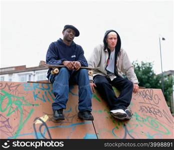 Boys sitting on skateboard ramp