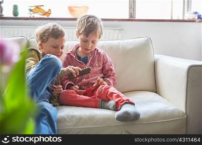Boys sitting on sofa looking at smartphone