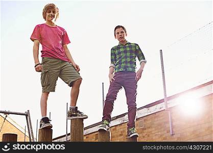 Boys standing on wooden poles