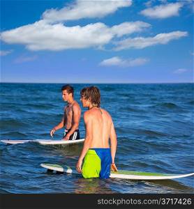 boys surfers waiting for the waves on the blue beach