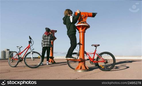 boys with bicycles looking through telescopes outdoors