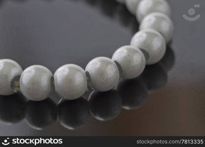 Bracelet of pearls over a black reflecting background