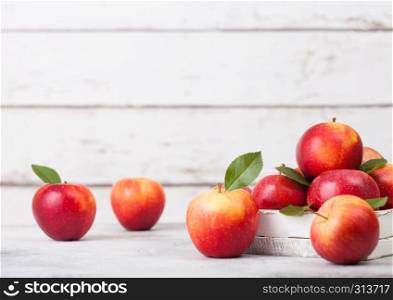 Braeburn pink lady apples in wooden box on white wood background
